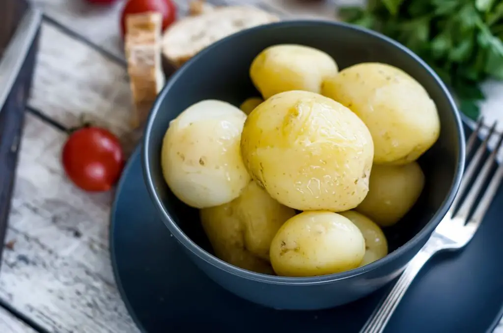 An image of Tasty boiled potatoes in black bowl.