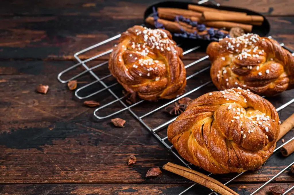 An image of a Homemade fresh baked Cinnamon buns or rolls, Swedish Kanelbullar. Dark wooden background.