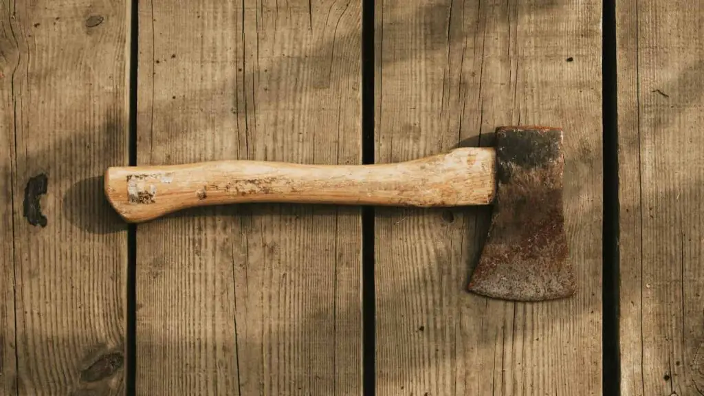 An image of a Rustic axe on a wooden background flatlay.