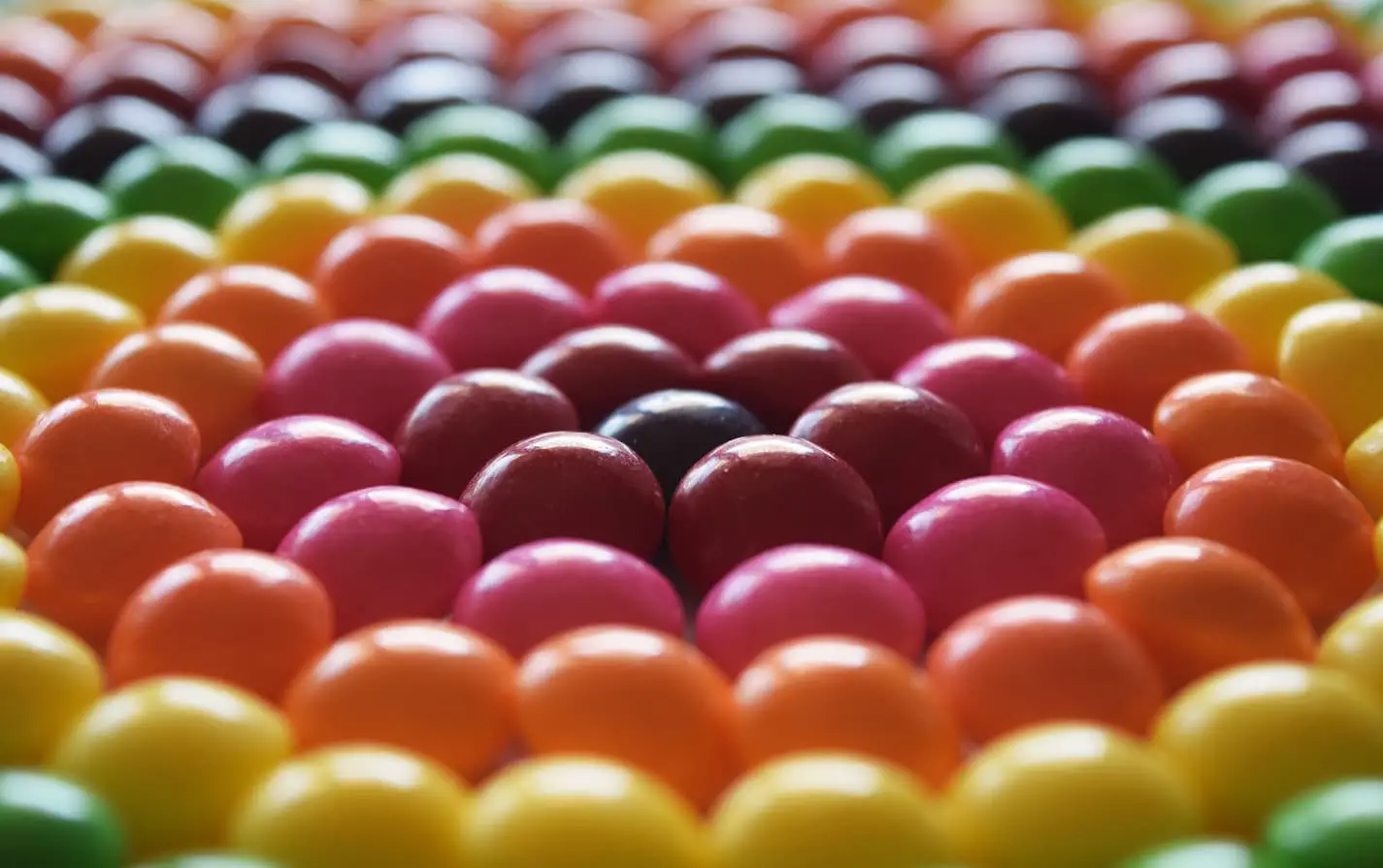 An image of skittles arranged in a rainbow.