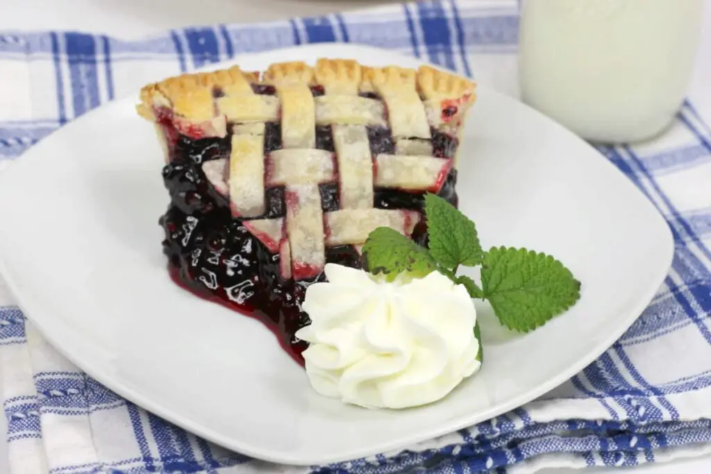 image of a slice of blackberry pie with whipped cream