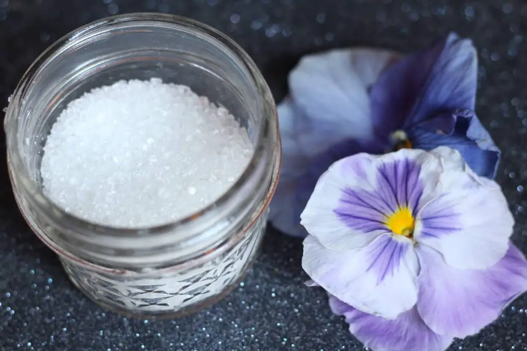 An image of Epsom salt in a bottle with flowers on the side.