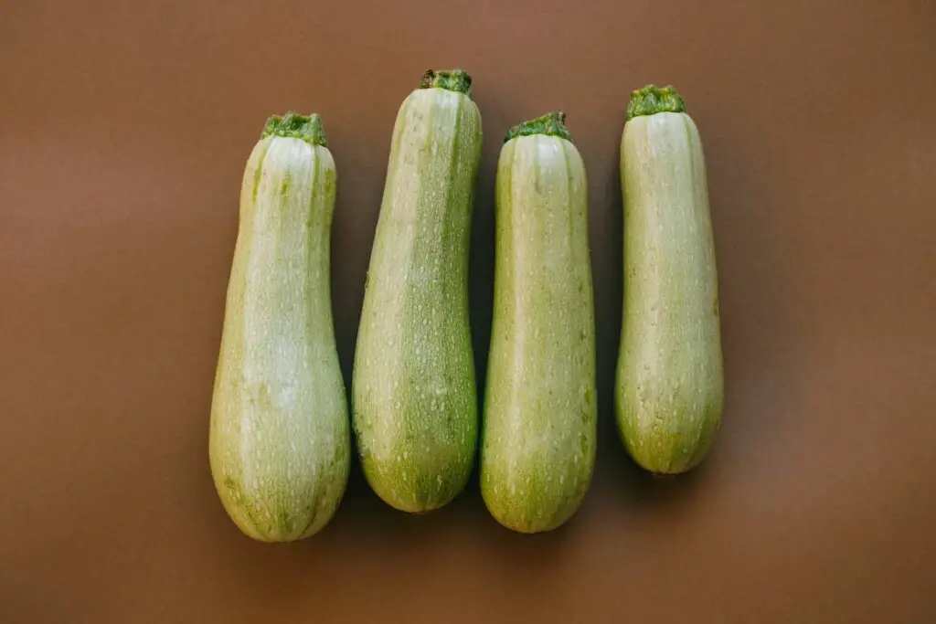 A top view image of four harvested zucchini on a brown background.