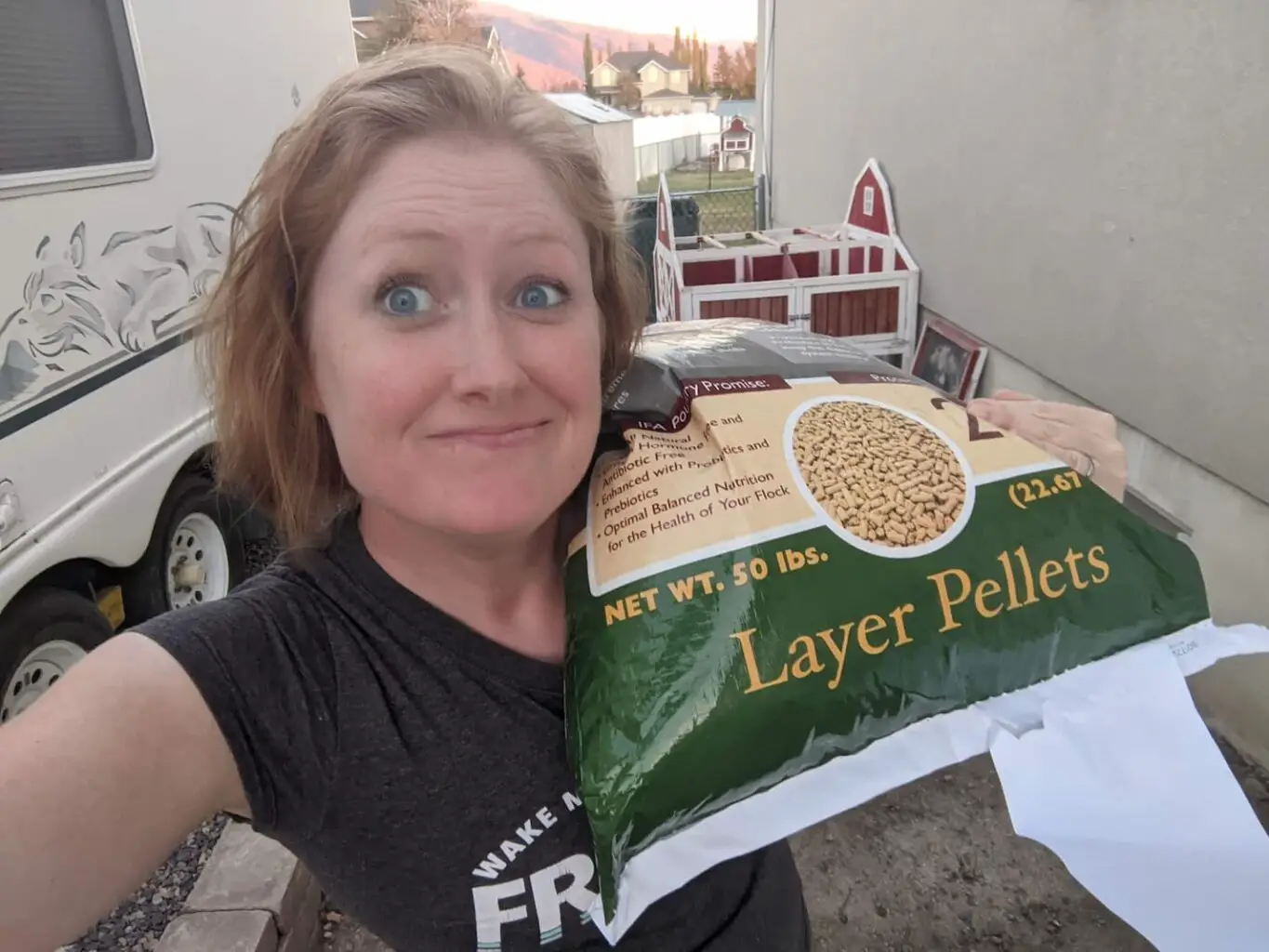 An image of Kimberly Starr carrying a 50-pound bag of chicken feed.