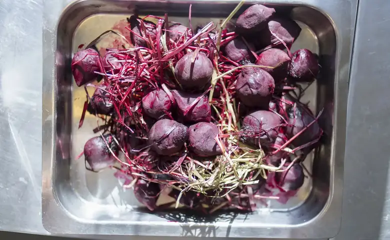 An image of raw beets in a silver tray.