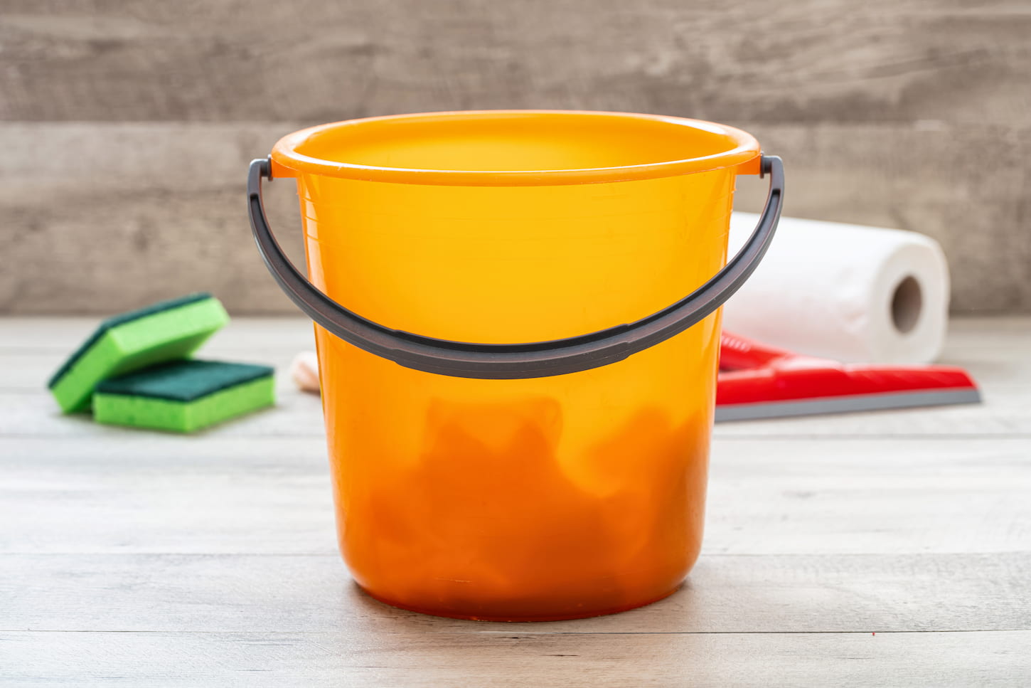 An image of a home depot style orange bucket on a wooden floor background.