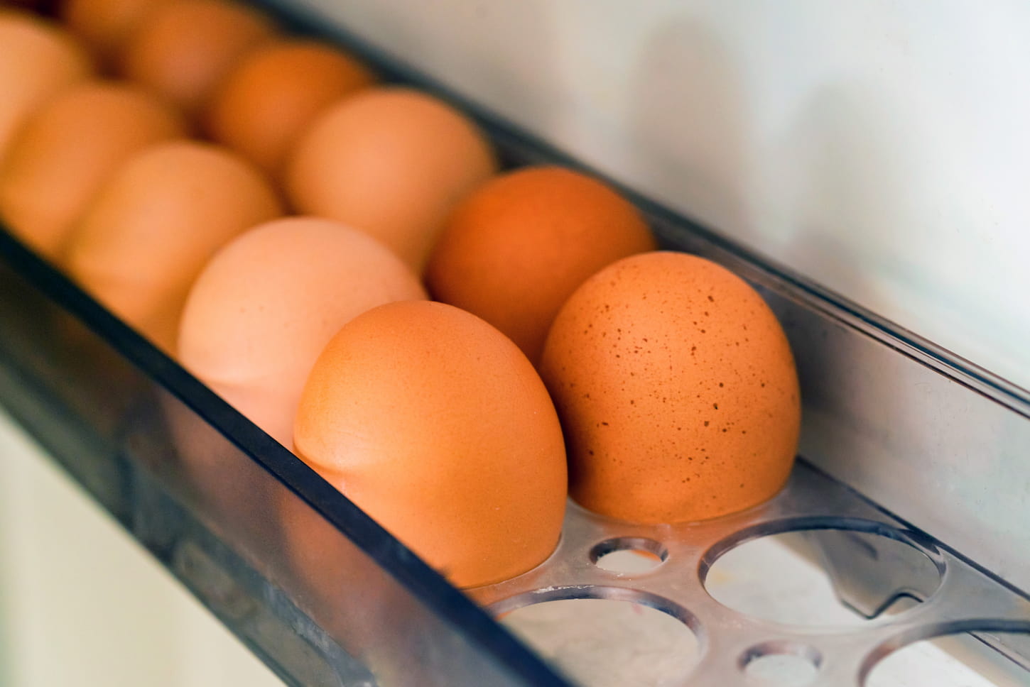 An image of raw farm brown eggs in the fridge.