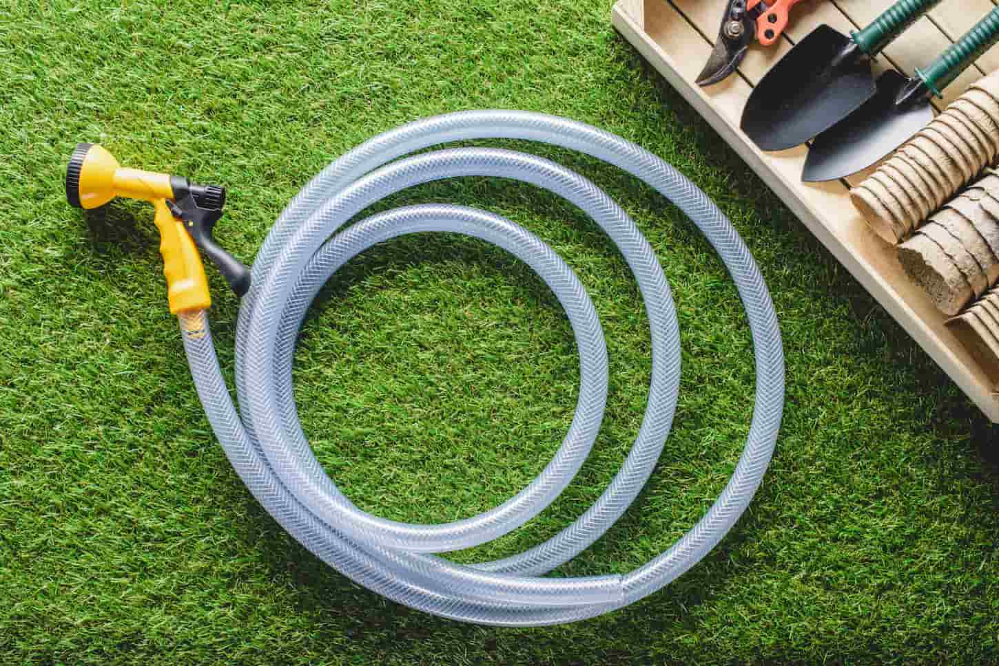 A top-view image of a garden hose on a grass floor background.