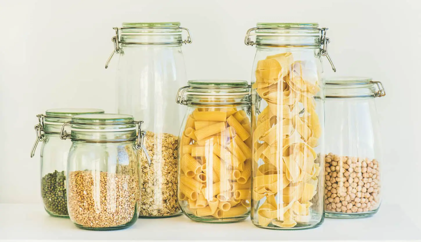 An image of uncooked cereals, grains, beans and pasta in jars.