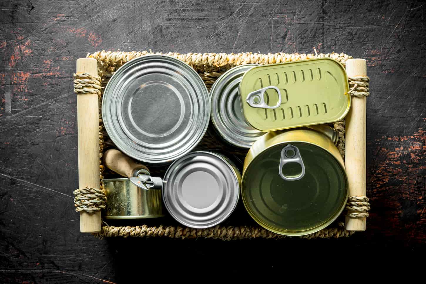 An image of Various closed cans on tray on a dark rustic background.
