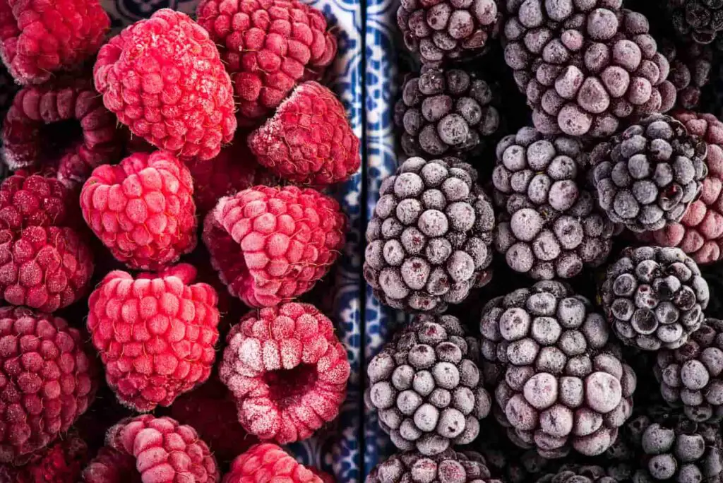 An image of frozen blackberry and raspberry fruits in separate bowls.