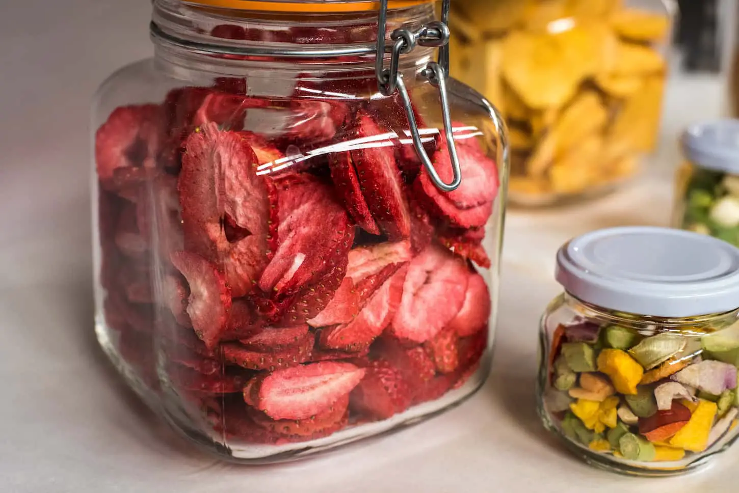 An image of freeze-dried strawberries and various vegetables in separate jars.