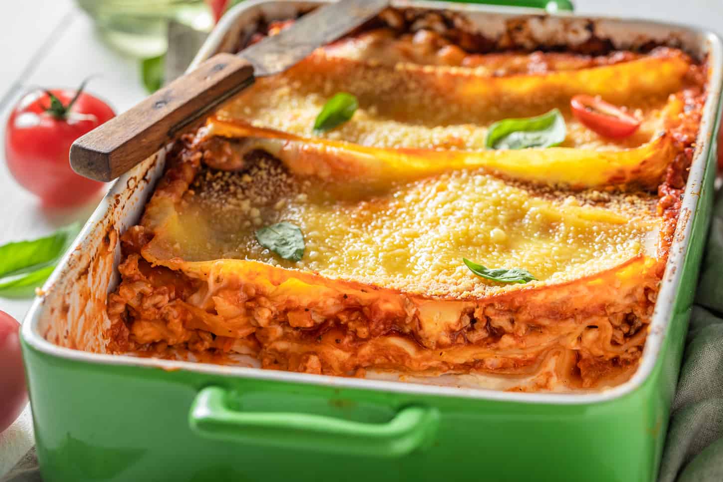 An image of Spicy lasagna baked in a casserole with cheese on a green tray.