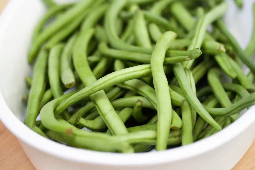An image of fresh green beans on a white bowl.