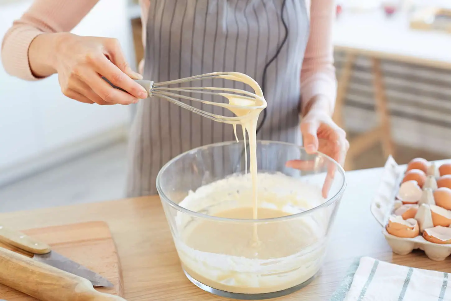 An image of a woman making dough using a whip.