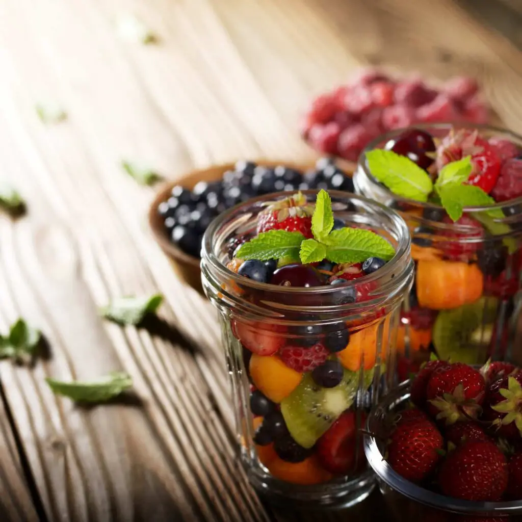 An image of Assorted berries in a mason jar on a kitchen wooden table.