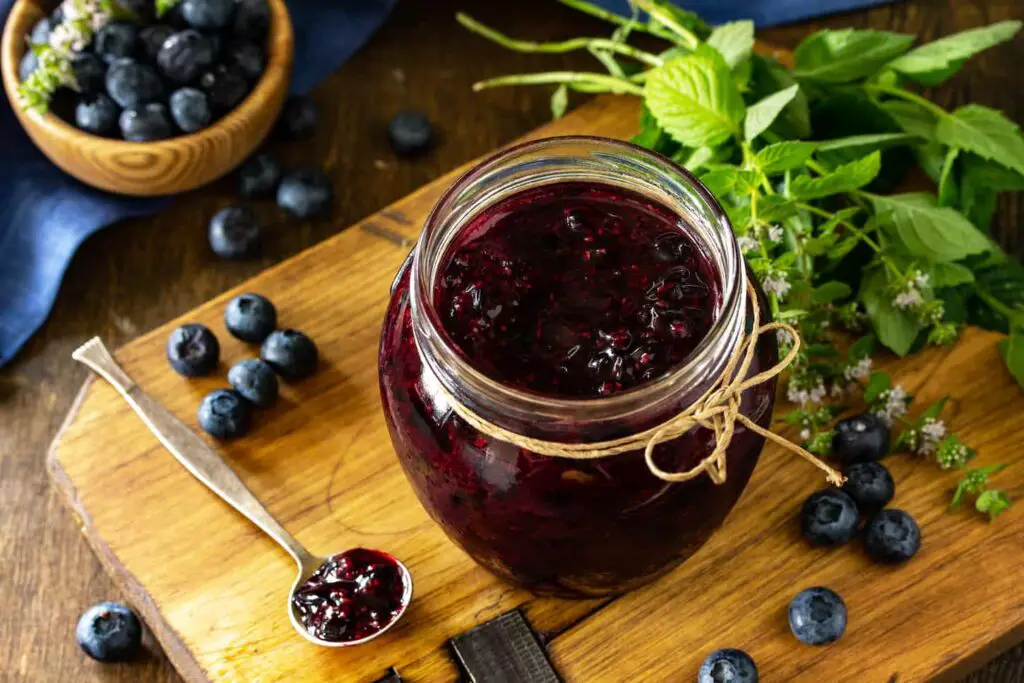 An image of Organic Homemade Preserves. Blueberry jam in a jar and fresh blueberries on rustic wooden table.