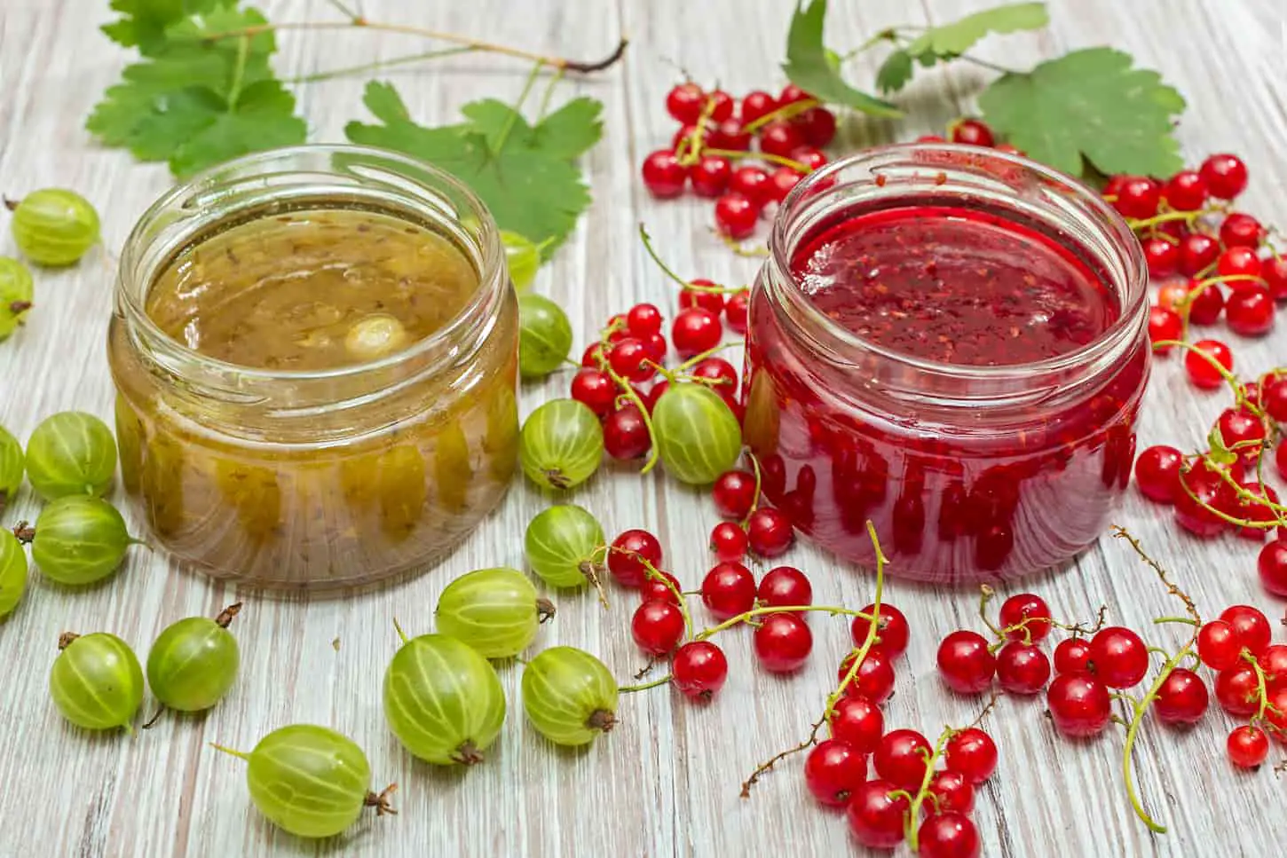 An image of Gooseberry jam and fresh berries, on a light wooden background.