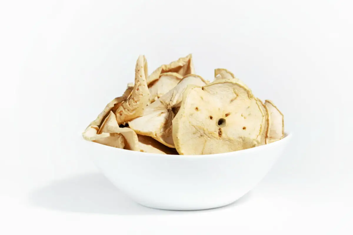 An image of Dry apple chips on a white plate isolated on a white background. Dehydrated food.