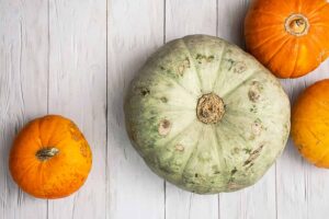 An image of vibrant pumpkins on a white wooden background.