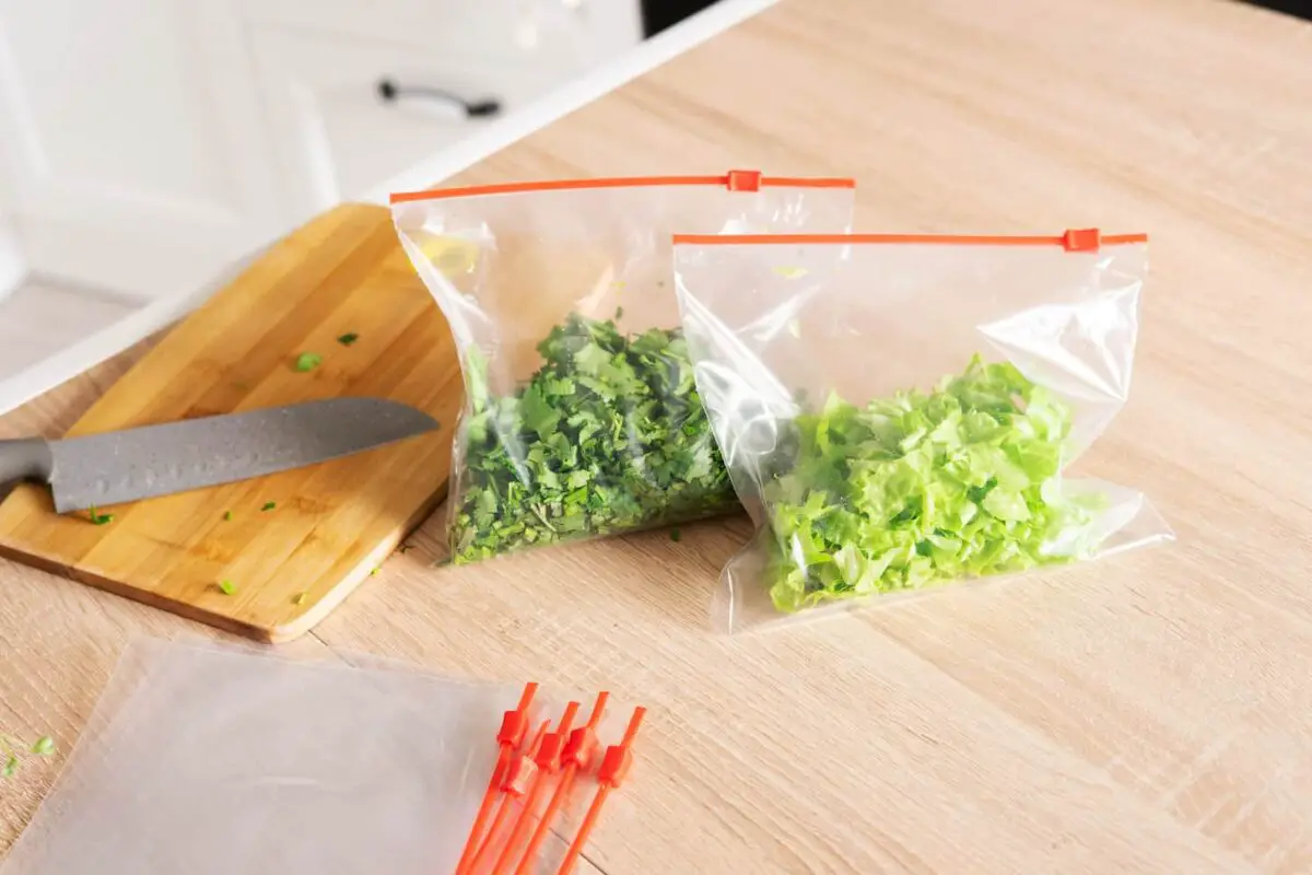 An image of Cilantro and lettuce in zip bags on the kitchen counter.